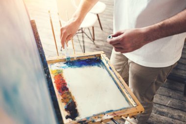 Erkek sanatçı Studio Palette renkleri karıştırır. Ressam atölye. Lens flare etkisi