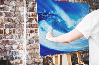 Erkek sanatçı tutun fırça ve ealse tuvalinde çizim. Boya atölyesinde çalışan ressam. Sanat alanı