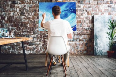 Boya yağlı boya sanat Studio bir tuval önünde bir sandalyede otururken sanatçıdır. Loft atölyede çizim süreci, ressam. Hobi kavramı