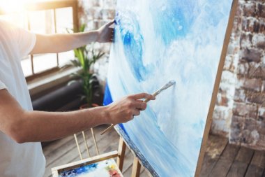 Sanat loft Studio oilpaints ile bir sanatçı çalışma çizim işlemi. Ressam tutun boya fırçası el tuval şövale üzerinde önünde. Hobi