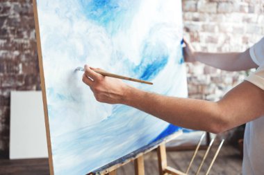 Adam sanatçı tutun fırça ve ealse tuvalinde çizim. Boya atölyesinde çalışan ressam. Sanat alanı
