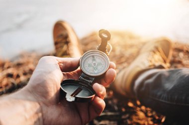 Dostum Gezgin tutun pusula yürüyüş ayakkabıları içinde arka plan ayak üzerinde elinde. Arka plan bulanık. Parlama efekti