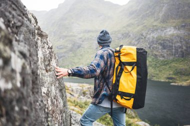 Yüksek dağda sırt çantası ile Tek başına profesyonel gezgin kenar uçurum kaya üzerinde duran ve uzağa bakıyor. Macera yaşam tarzı tatil