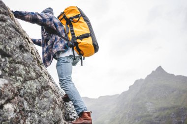 Profesyonel sırt çantalı cesur bir dağcı kayaya tırmanıyor. Aktif korkusuz turistler dağda toplanıyor. 