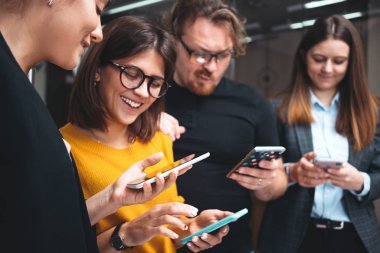 Bir grup pozitif iş adamı birlikte çalışıyor ve ofisteki modern akıllı telefonu kullanıyorlar. Konsept kullanan dijital aygıtlar