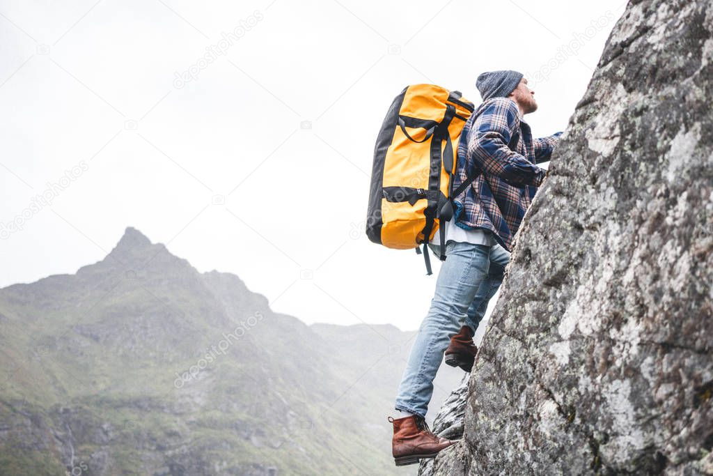 Climber man tourist wearing professional backpack to climb on the rock. Brave lifestyle man tourist conquers the mountains