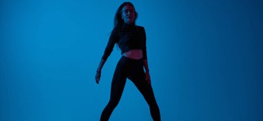 Hayalet mavisi arka plana karşı yakışıklı genç bir kadının portresi. Stüdyoda poz veren atletik kız. Geniş resim