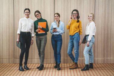 Ortak çalışma alanındaki grup başarısının portresi. Genç ve neşeli iş adamlarından oluşan bir ekip bir arada duruyor ve gülüyorlar.