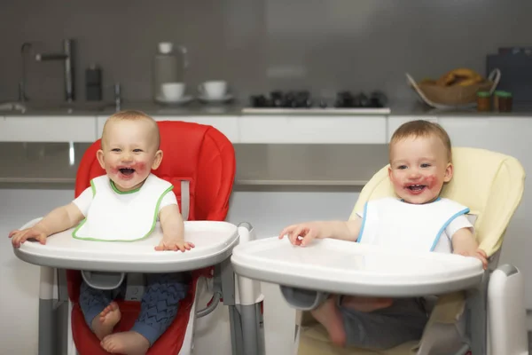 Kinderen eten bosbessen in een hoge kinderstoel. De jongens hebben een vies gezicht — Stockfoto