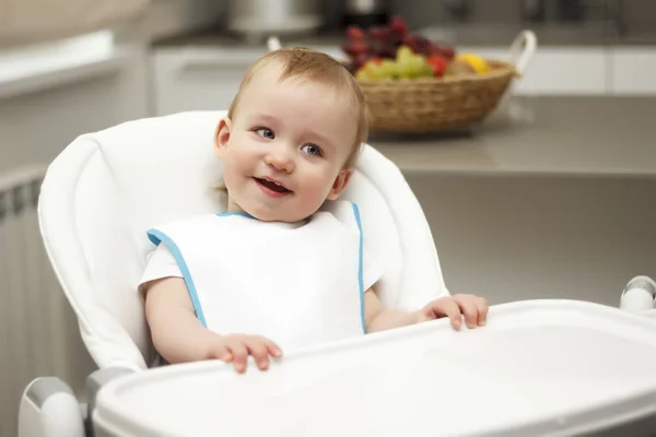 Kleine jongen in een hoge stoel zitten en lachen — Stockfoto