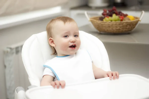 Gelukkig peuter in de kinderstoel zitten en eten van PAP. Baby leren om te eten en yoghurt heeft op PAP. — Stockfoto