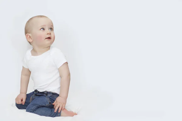 Een jongen met blauwe ogen in spijkerbroek op een witte achtergrond — Stockfoto