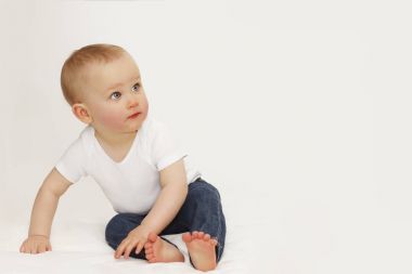 Kot ve beyaz bir T-shirt gri bir arka plan üzerinde mavi gözlü bir çocuk portresi