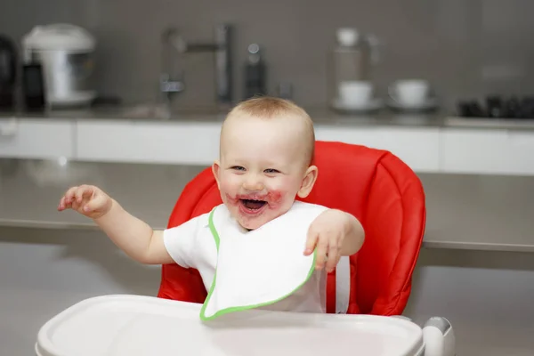 Kleine jongen in een hoge stoel zitten en lachen — Stockfoto