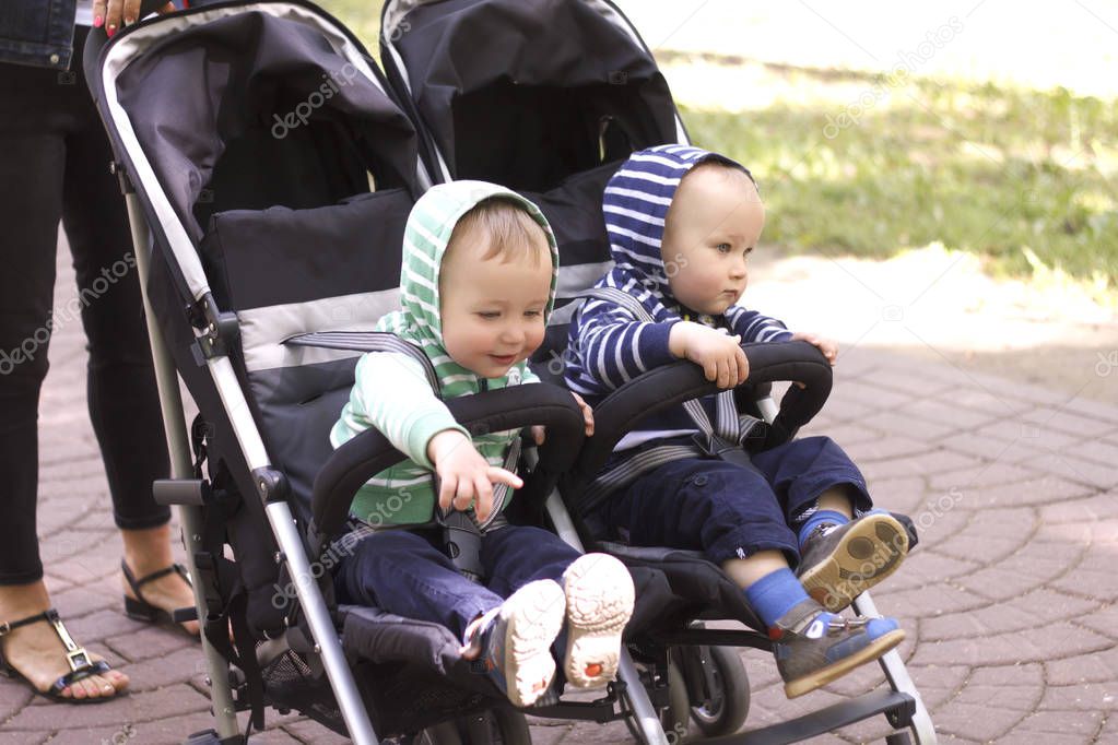 two boy twins in a stroller in the street