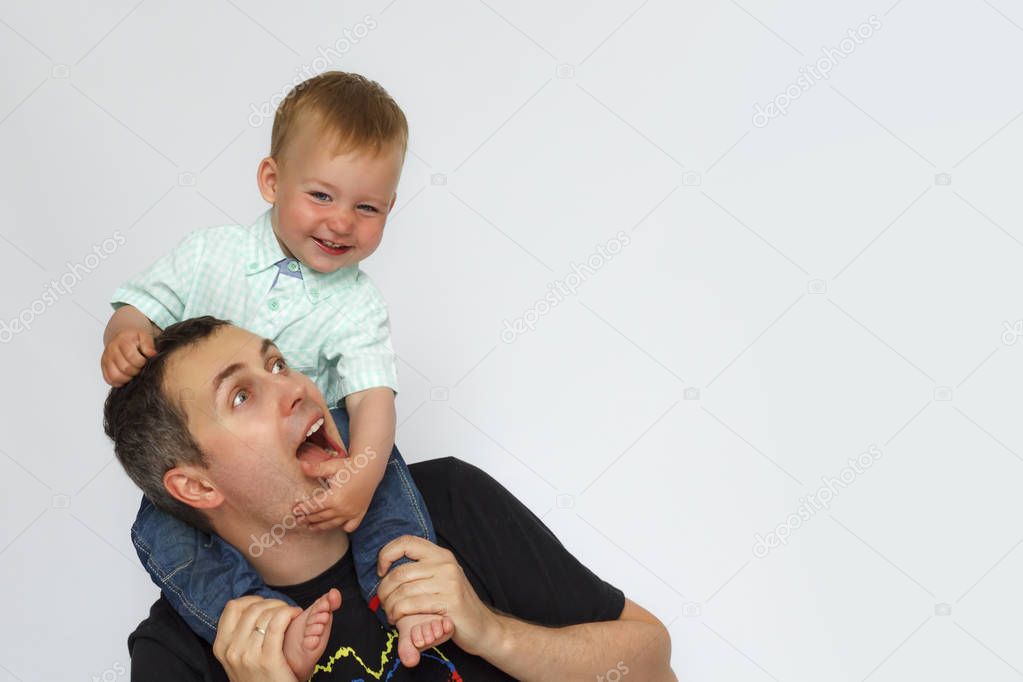 Baby sitting on father neck on white background