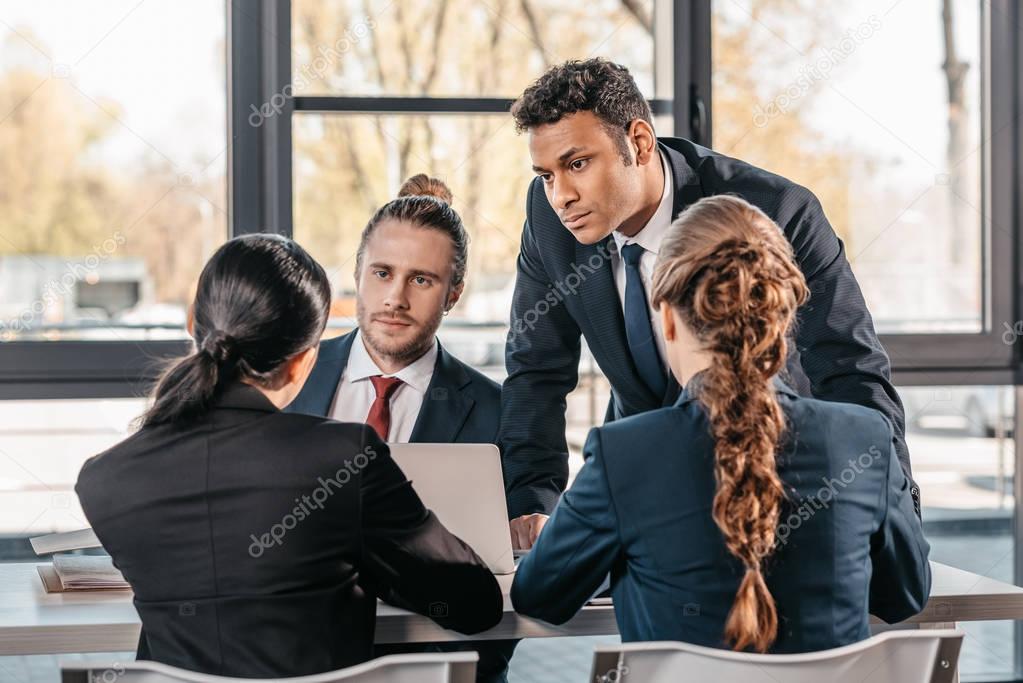 coworkers in formalwear arguing at business meeting