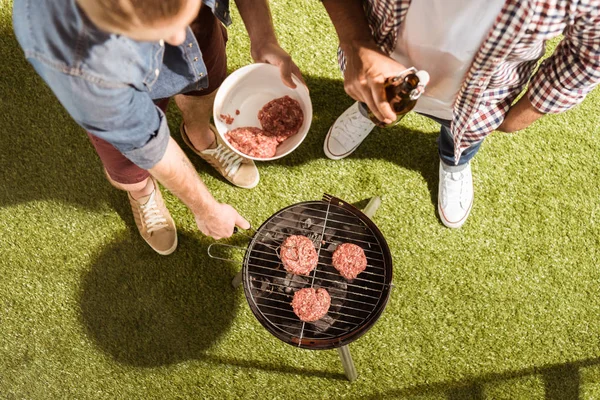 ハンバーガーを焼く若い男性 — ストック写真