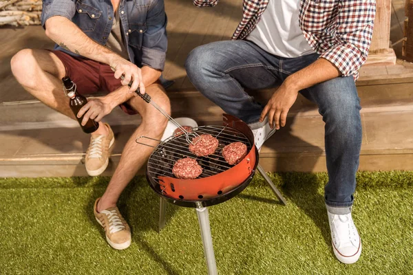 Jeunes hommes grillant des hamburgers — Photo