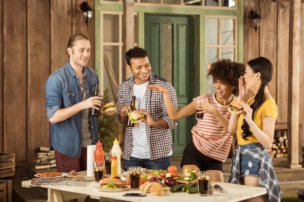 Amigos multiétnicos comiendo hamburguesas en el picnic — Foto de Stock