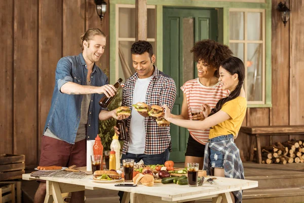 Multietniskt vänner äta hamburgare på picknick — Stockfoto