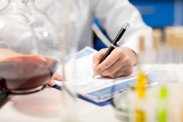 Científico escribiendo en bloc de notas - foto de stock