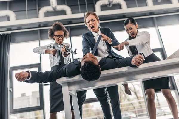 Empresarias castigando a hombre de negocios - foto de stock