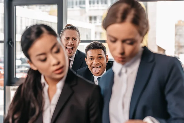 Empresarios haciendo muecas a mujeres de negocios - foto de stock