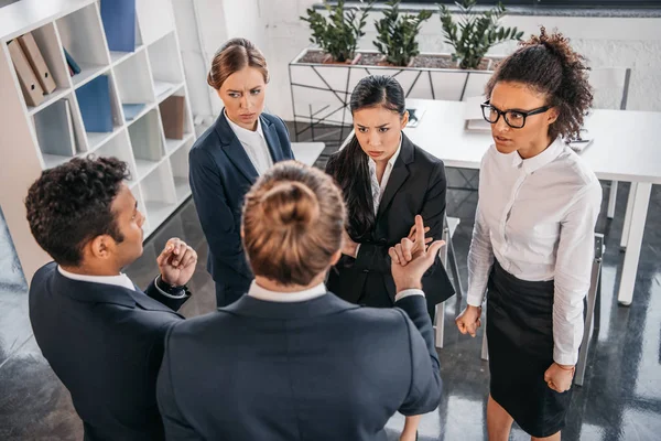 Compañeros de trabajo en ropa formal argumentando en la reunión de negocios - foto de stock