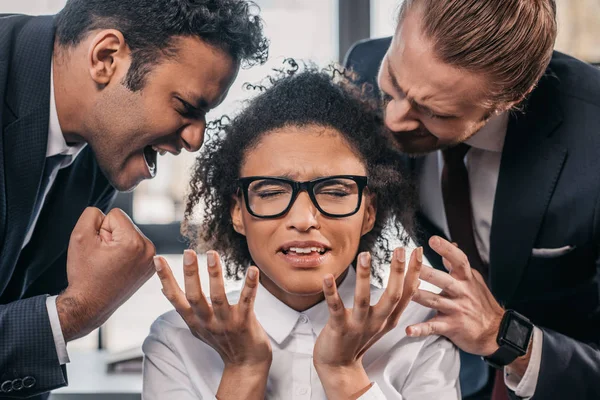 Businessmen screaming on businesswoman in office — Stock Photo