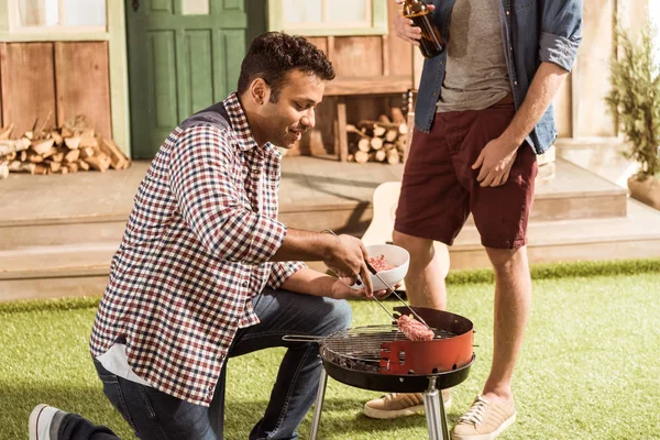 Men grilling burgers — Stock Photo