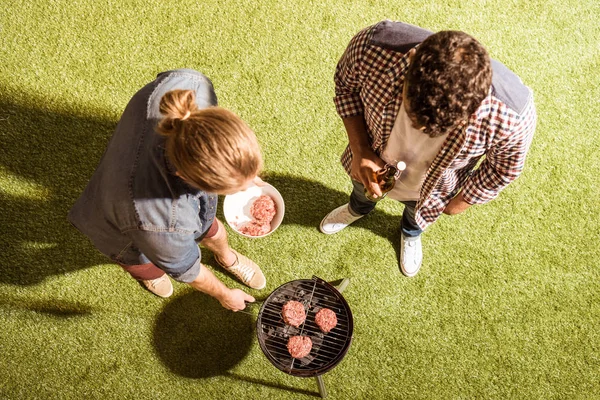 Young men grilling burgers — Stock Photo
