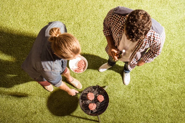 Hombres jóvenes asando hamburguesas - foto de stock