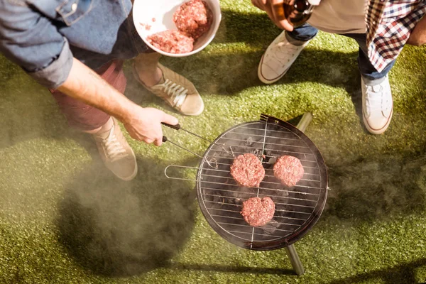 Giovani uomini grigliare hamburger — Foto stock