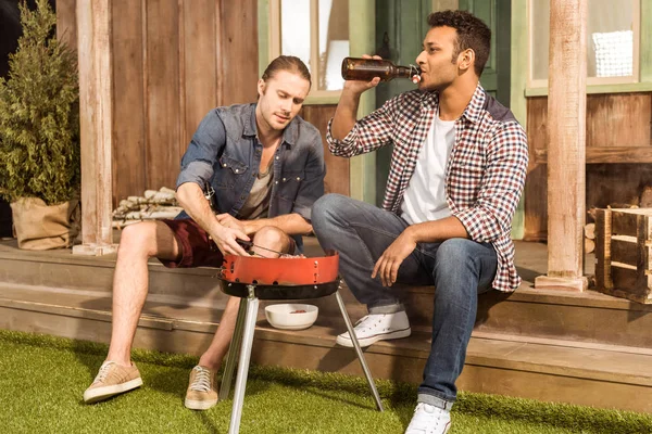 Hombres jóvenes asando hamburguesas - foto de stock