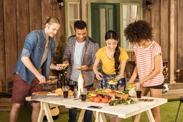 Amigos multiétnicos haciendo hamburguesas en el picnic - foto de stock