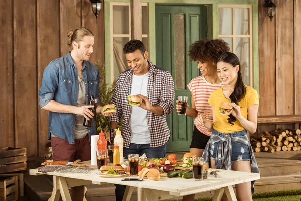 Amigos comiendo hamburguesas y bebiendo cola - foto de stock