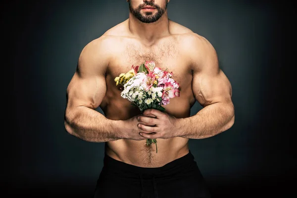 Sportive man with bouquet of flowers — Stock Photo