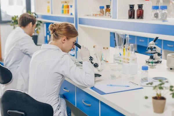 Scientists with microscopes in laboratory — Stock Photo