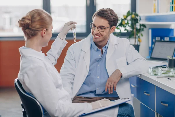 Biologen halten Fläschchen mit Pflanze — Stockfoto