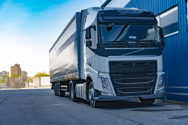 Een vrachtwagen met een tentaanhanger staat vlak bij het magazijn Stockfoto