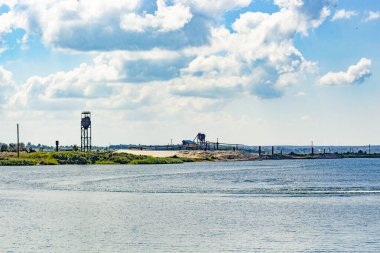 Gölün arka planında kumlu, boş bir sahil ve mavi gökyüzü. 