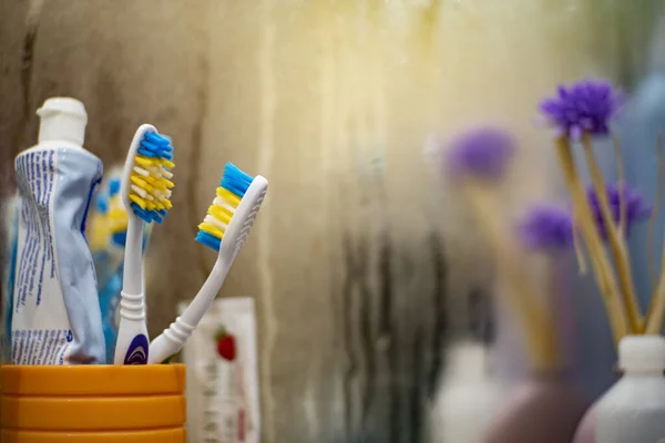 Tandenborstels zijn in een glas in de buurt van de bedekte spiegel 1 Stockafbeelding