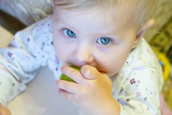 Een klein meisje met blond haar met een groene tomaat in haar hand 1 Rechtenvrije Stockfoto's