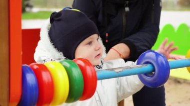 Küçük kız oyun alanında yüzüklerle oynuyor.