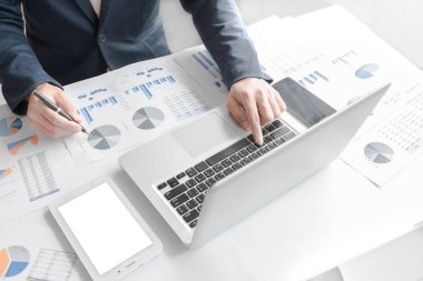 Dizüstü bilgisayar, tablet ve grafik dat ile ofisinde çalışan iş adamı