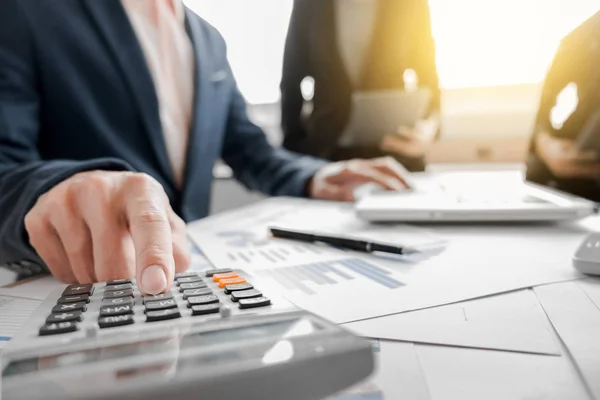 Business team met behulp van een calculator voor het berekenen van de nummers op zijn — Stockfoto