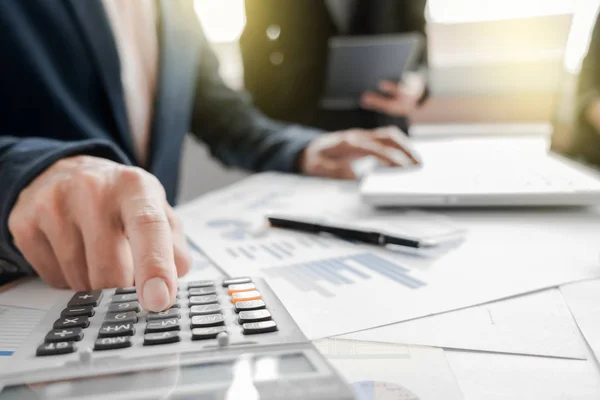 Business team using a calculator to calculate the numbers on his — Stock Photo, Image