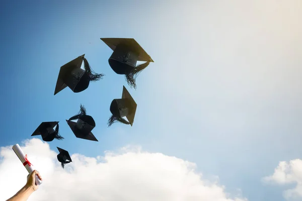 Afgestudeerden handen gooien afstuderen hoeden. — Stockfoto