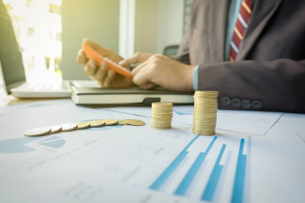 Hombre de negocios usando calculadora con monedas apiladas arregladas en offi — Foto de Stock